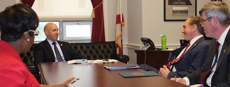 Congressman Brian Mast (R-FL-18) speaking with other people in his office.